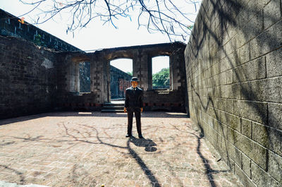 Rear view of man standing by building against sky