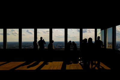 Silhouette people sitting by window in city