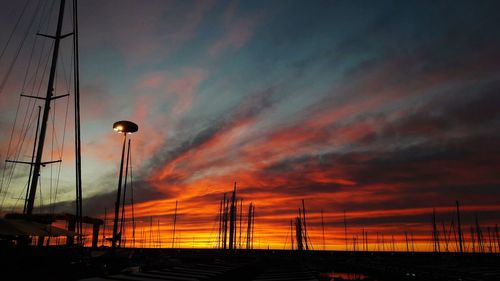 Silhouette sailboats on street against dramatic sky during sunset