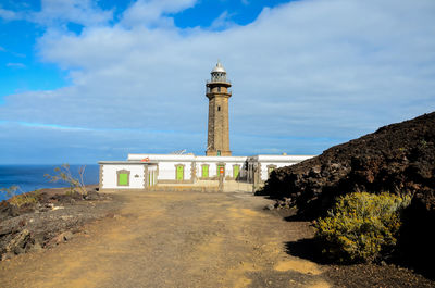 Lighthouse by sea against sky