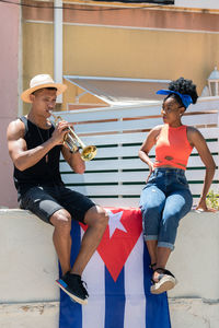 Full length of man holding woman sitting outdoors