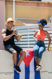 Full length of man holding woman sitting outdoors