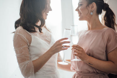 Bridesmaid and bride holding champagne flute