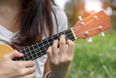 Midsection of woman playing ukulele on grass