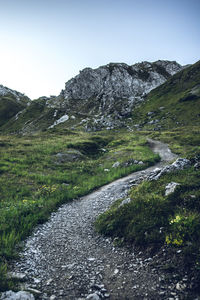 Road leading towards mountains against clear sky