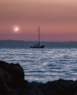 Silhouette sailboat in sea against sky during sunset