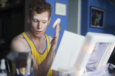 Young man applying face powder