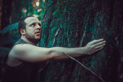 Portrait of young man looking away in forest