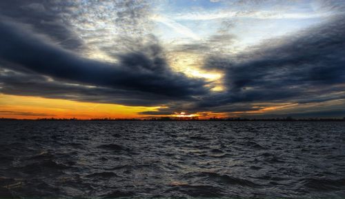 Scenic view of sea against cloudy sky during sunset