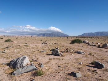 Scenic view of rocks on field against blue sky