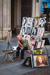 Full length of man sitting on street at market