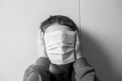 Full length portrait of a teenage girl covering face against wall