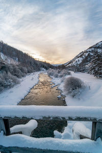 River in winter with snow, sunset and light reflection on water