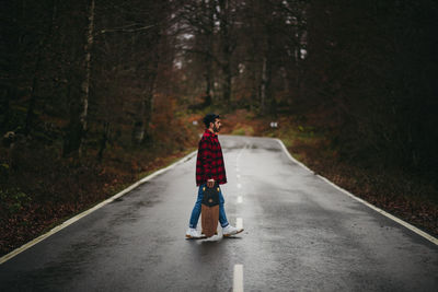 Rear view of man on road in forest