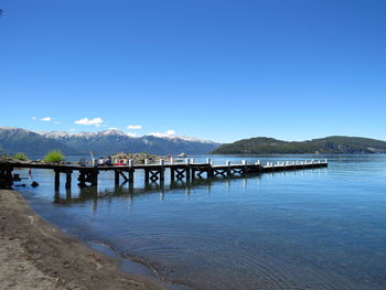 Pier over sea against blue sky