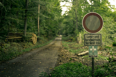 Road sign by trees in forest