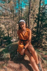 Portrait of smiling woman sitting on tree trunk