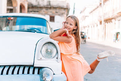 Smiling girl looking away while standing by car