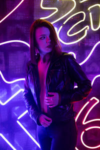 Portrait of young woman standing against wall