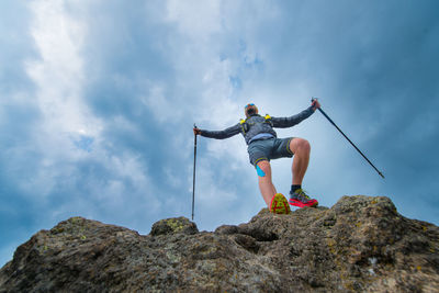 Low angle view of person on rock against sky