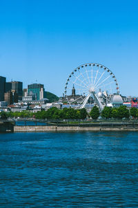 Ferris wheel in city against blue sky