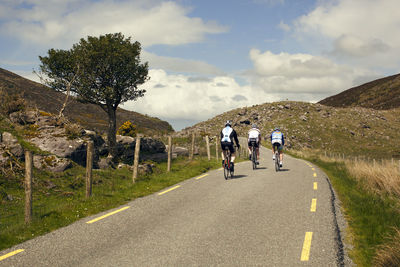 Rear view of cyclist riding bicycle on gap of dunloe against sky