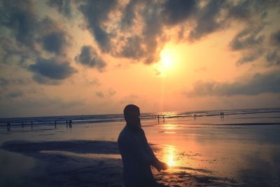 Woman standing on beach during sunset