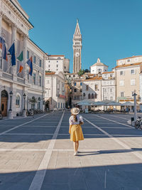 Rear view of young woman standing in square of idyllic town of piran, slovenia