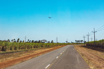 Road amidst field against clear sky