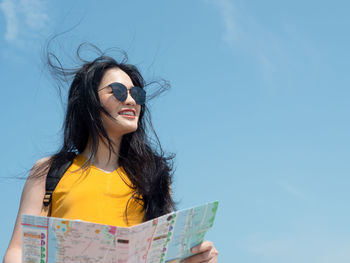 Portrait of smiling young woman against blue sky