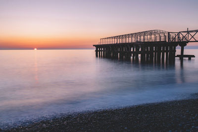 Pier over sea against sky during sunset