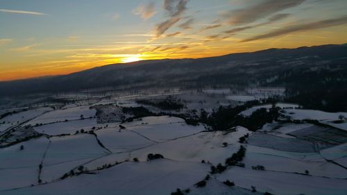 Snow covered field at sunset