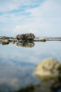 Reflection of rocks in sea against sky