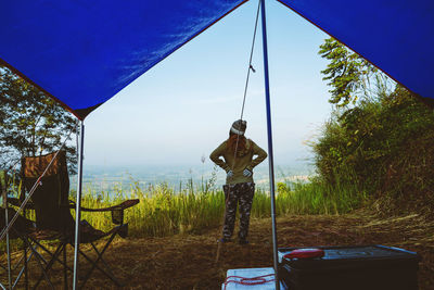 Rear view of woman standing by tent against sky