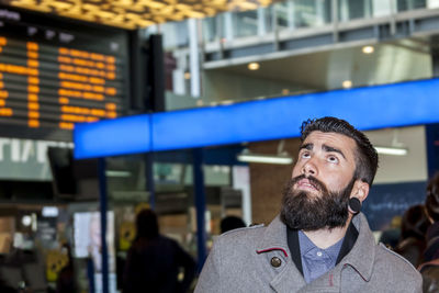 Hipster businessman consult the board of timetable trains