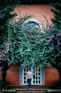 Woman standing on porch amidst trees against door