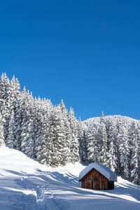 Snow covered landscape against clear blue sky