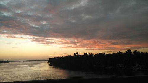 Scenic view of calm sea against cloudy sky during sunset