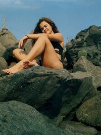 Low angle view of young woman sitting on rock