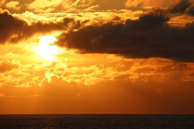 Scenic view of sea against dramatic sky during sunset