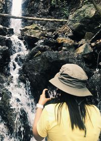 Midsection of woman on rock at waterfall