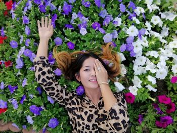 High angle portrait of smiling woman lying on flowers