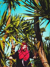 Portrait of young woman with palm tree