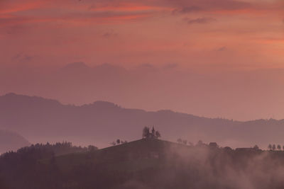 Scenic view of silhouette mountains against orange sky