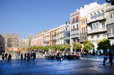 People on street against buildings in city