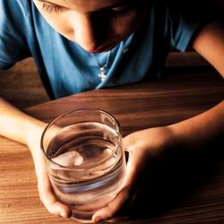 Close-up of boy looking ice in glass on table