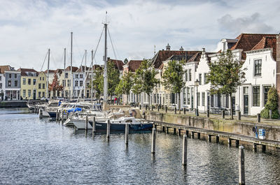 Boats moored at harbor against buildings in city