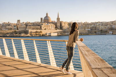 Woman standing on promenade by sea