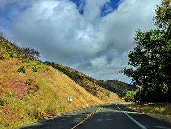 Empty curved road along mountain landscape and against cloudy sky