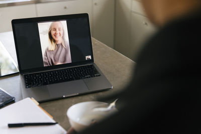 Businesswoman talking with businessman through video call on laptop at home